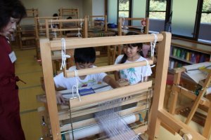 （写真）機織り体験をする子供たち