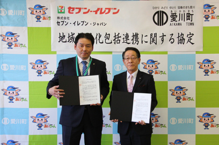 （写真）協定書を持って並ぶ株式会社セブン‐イレブン・ジャパンの林賢司西神奈川ゾーンマネジャーと小野澤町長