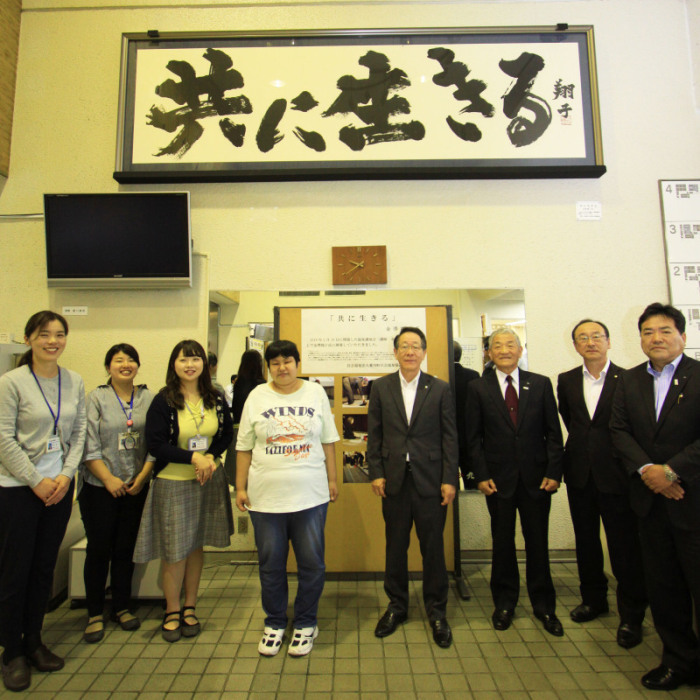 （写真）書の下に並ぶ町幹部職員・町社会福祉協議会幹部職員