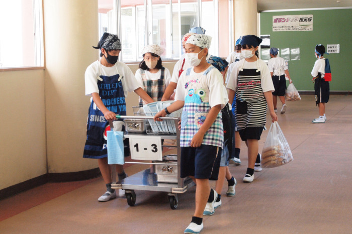 （写真）食缶を運ぶ生徒たち