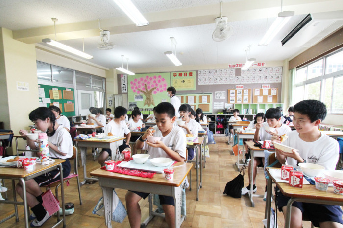 （写真）教室で給食を食べる生徒たち