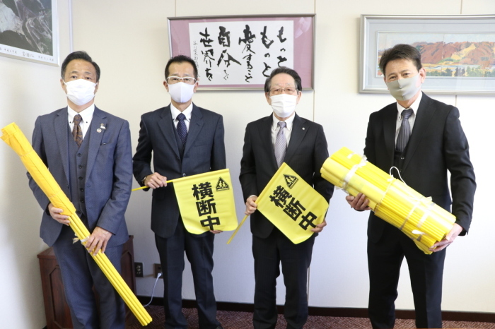 （写真）旗を持って並ぶ大塚淳副会長、鈴木地区会長、小野澤町長、坂本学副会長