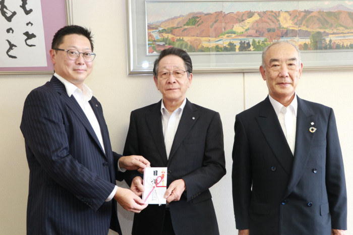 （写真）目録を手にして並ぶ小島代表取締役社長、小野澤町長、岡見代表取締役会長