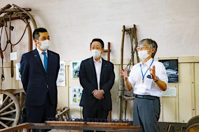 （画像）町学芸員から、昔の農機具や撚糸機械などの説明を受ける倉重市長（左）と小野澤町長（中央）