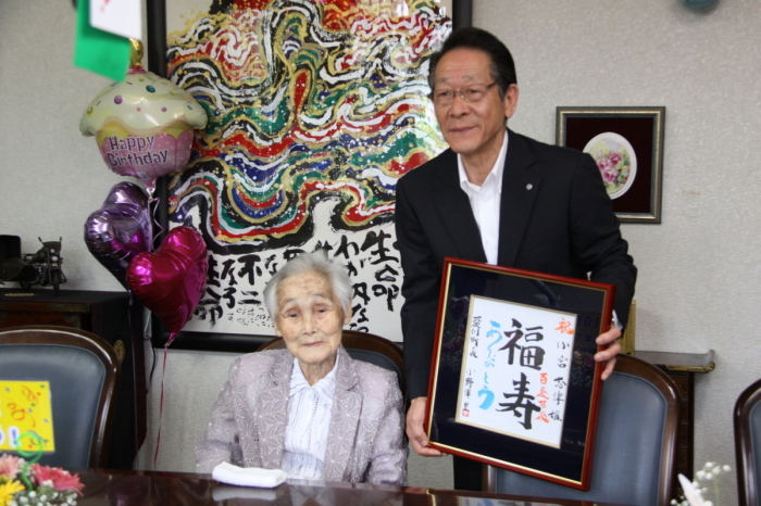 （写真）小宮さんにお祝いの額を渡す小野澤町長