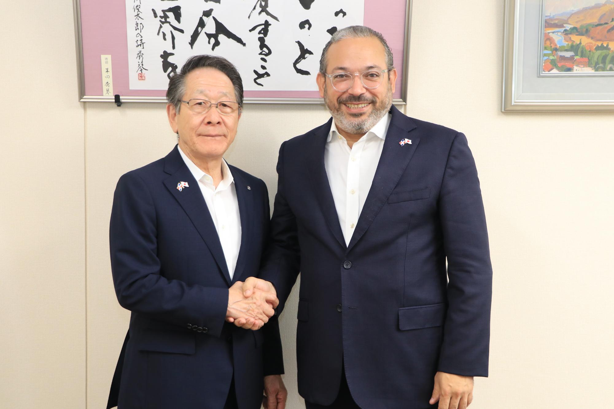 （写真）並んで握手をする小野澤町長とペレス大使