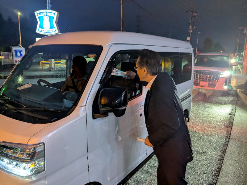 （写真）信号待ちの車のドライバーに啓発物品を手渡す小野澤町長
