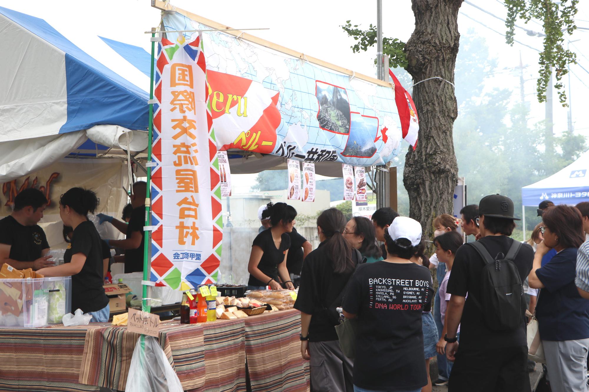 （写真）国際交流屋台村による各国の模擬店に並ぶ来場者の皆さん