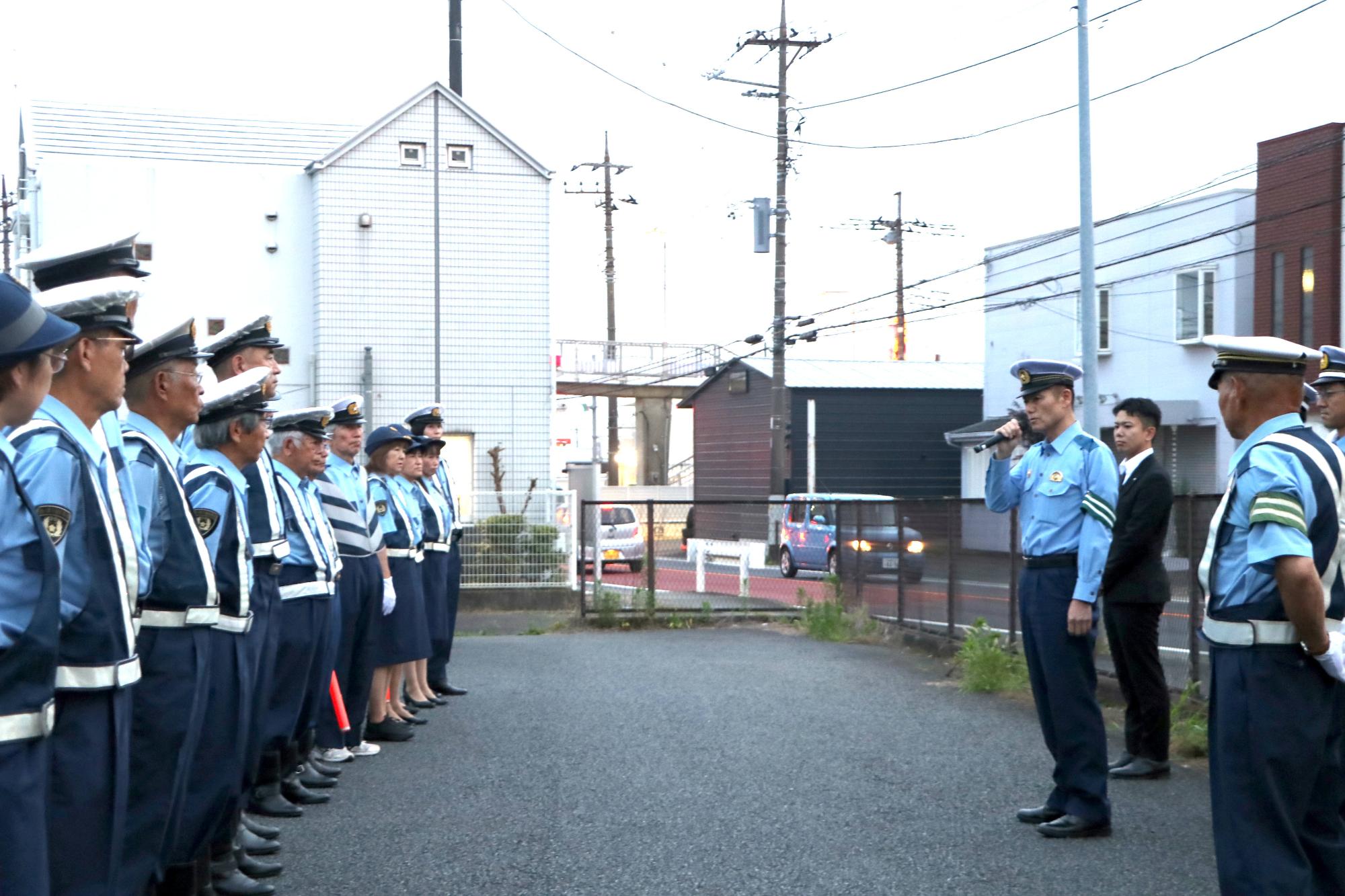 （写真）一列に並ぶ町交通指導隊の皆さんの前であいさつを述べる椎名厚木警察署長