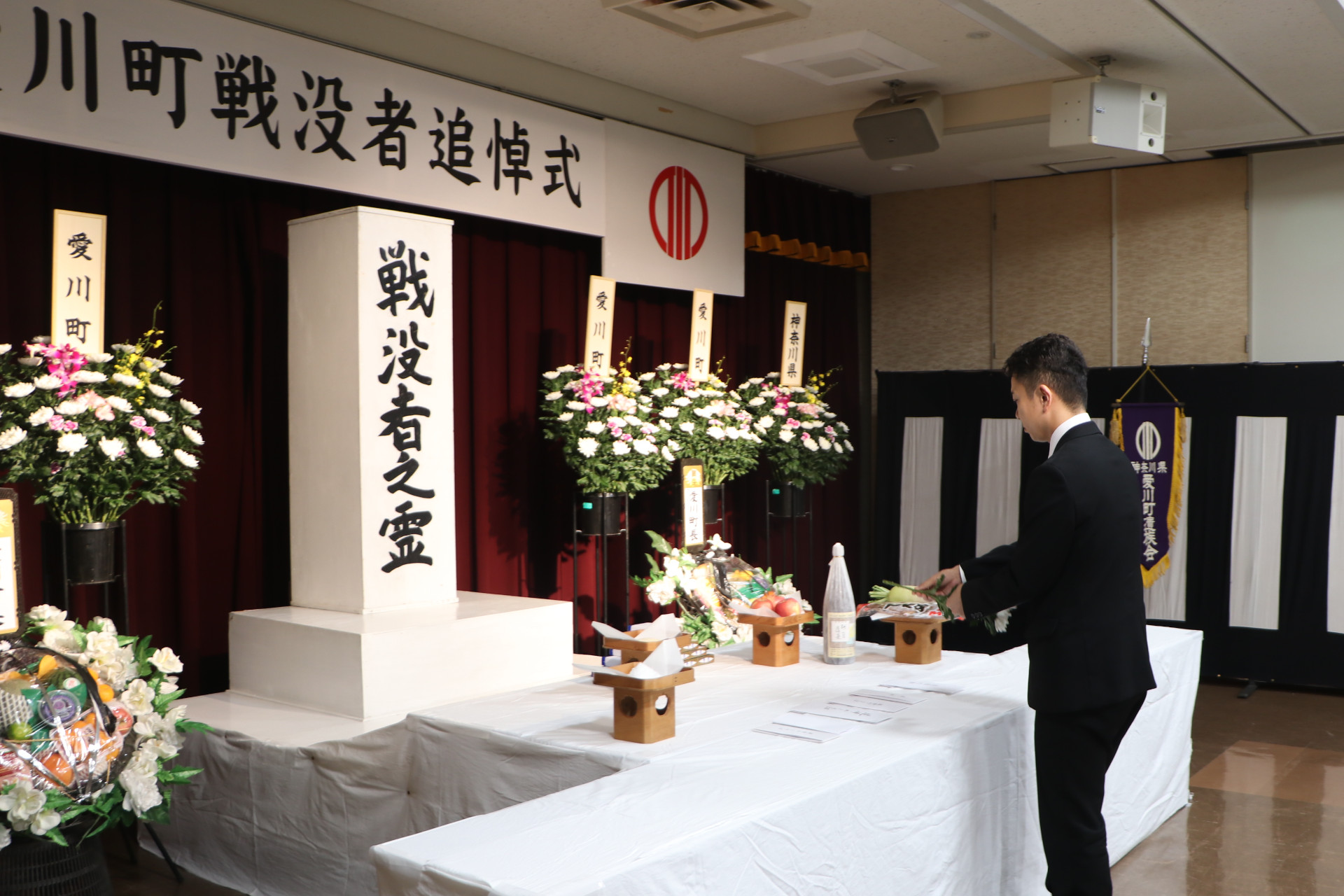 （写真）祭壇に向かい、献花をする茅町長